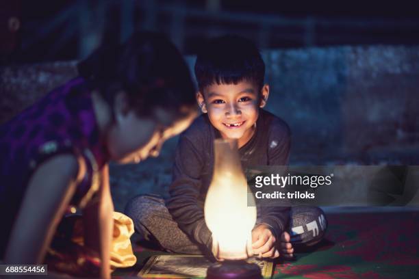 jongen en meisje studeren in olielamp - indian house stockfoto's en -beelden