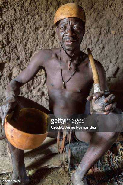 Portrait of one of the ancient men in Yaka with a traditional smoking pipe inside a hut. These people are the ones in charge of organising the...