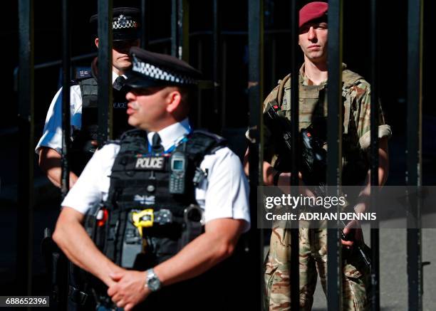 British army soldier from the Parachute Regiment stands alongside a police officer behind the gates to Downing Street, the official residence of...