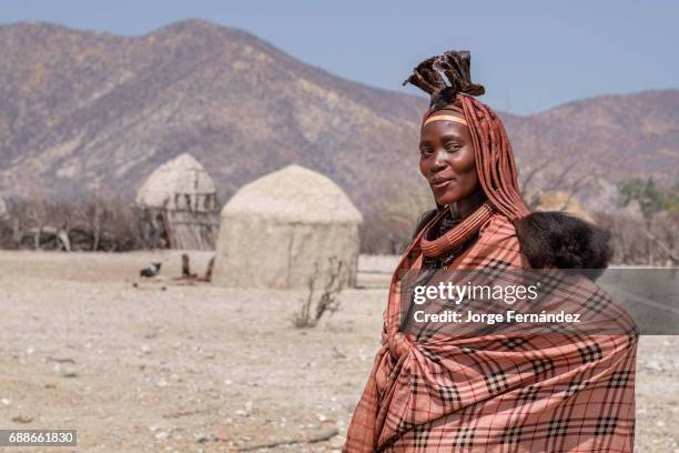 Portrait of a Himba woman in her village of mud huts. Himbas are a bantu tribe who migrated into what today is Namibia a few centuries ago. They...