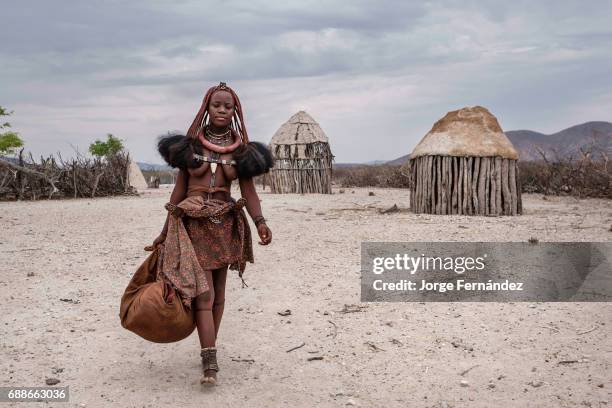 Himba woman ready to travel with her belongings in a village near Epupa falls. Himbas are a bantu tribe who migrated into what today is Namibia a few...
