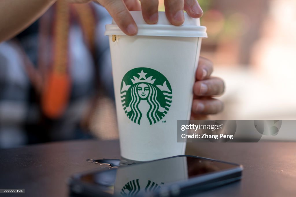 A girl holds a Starbucks coffee cup, resting at roadside...