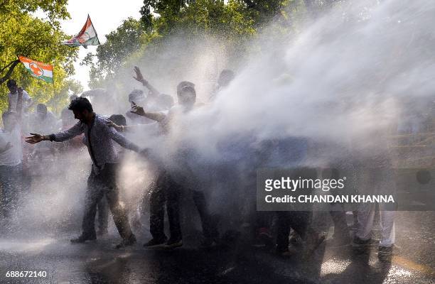 Activists with the Indian Youth Congress are hit with a water cannon fired by police during a protest following the completion of three years of...