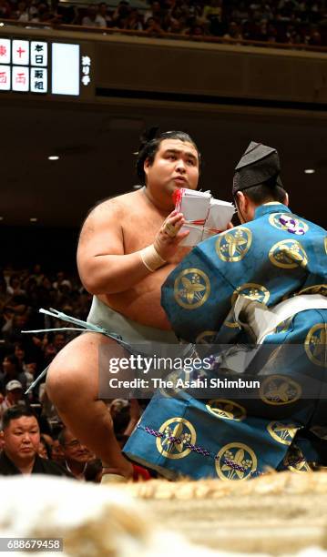 Sekiwake Takayasu receives envelopes containing prize money after his victory over Mongolian yokozuna Harumafuji during day thirteen of the Grand...