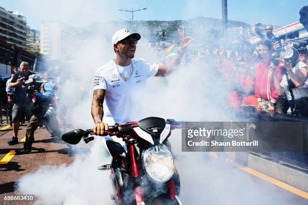 Lewis Hamilton of Great Britain and Mercedes GP performs a burnout on his motorbike for fans during previews to the Monaco Formula One Grand Prix at...