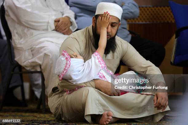 Muslim man with a young child attends Friday prayers at Manchester Central Mosque where they prayed for those who were killed or injured in the...