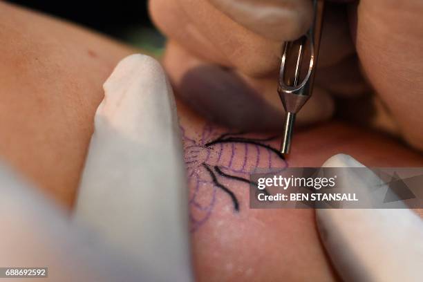 Tattoo artist inks a bee logo, synonymous with Manchester as a symbol of the city's industrial heritage, and rapidly becoming a symbol of resilience...