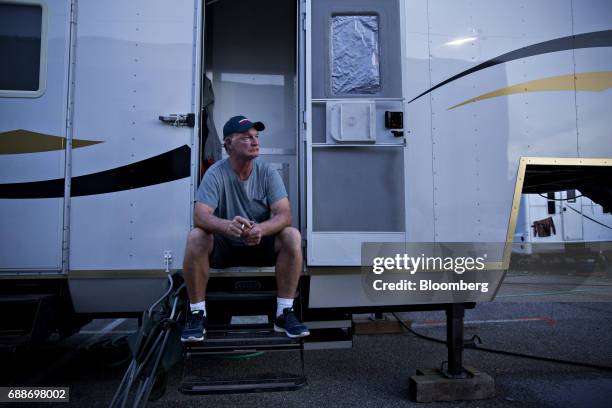 Ride operator and foreman smokes a cigarette outside his sleeping trailer during the Dreamland Amusements carnival in the parking lot of the Marley...