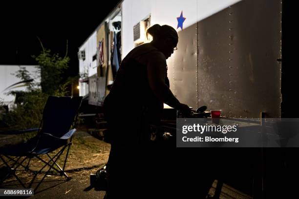 Game operator prepares a meal next to her sleeping trailer after the Dreamland Amusements carnival closed for the night in the parking lot of the...