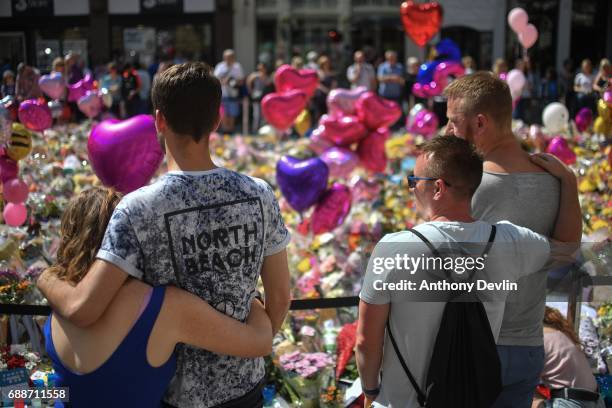 Couples comfort one another as flowers and balloons are left in Saint Ann's Square in tribute to those killed in an explosion at the Manchester Arena...