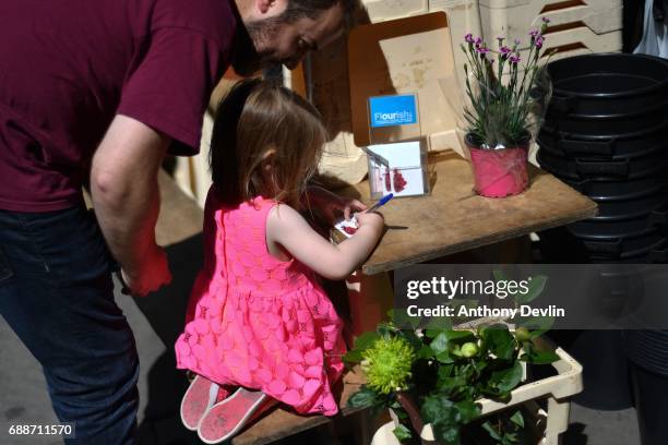 Young girl writes a note as people continue to leave flowers in tribute to those killed in an explosion at the Manchester Arena earlier this week on...