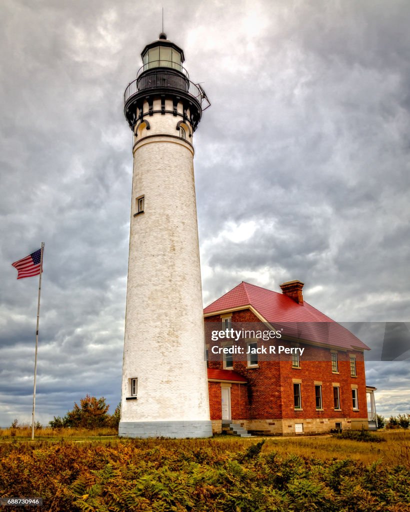 Au Sable Lighhouse with Waving Flag, clouds, red brick vertical