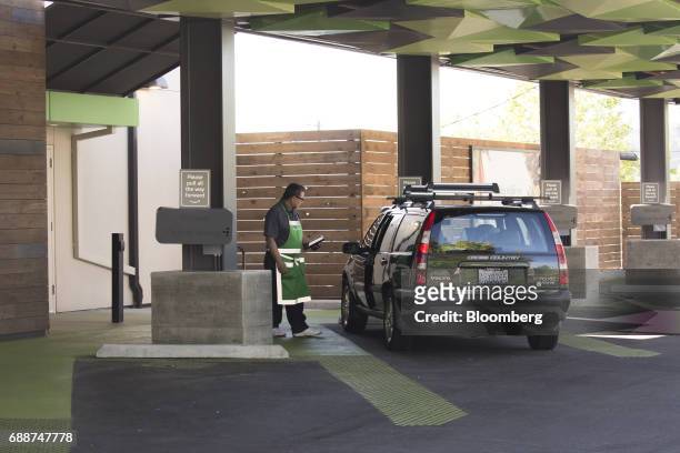 An employee assists a customer at an AmazonFresh Pickup location in Seattle, Washington, U.S., on Friday, May 26, 2017. Amazon.com Inc. Opened two...