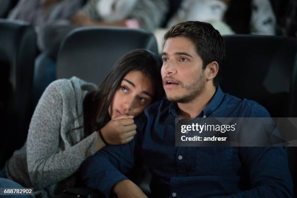 portrait of a couple watching a scary movie at the cinema - woman watching horror movie stock pictures, royalty-free photos & images