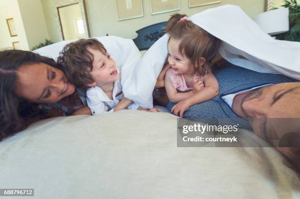 family playing on a bed. - family cover stock pictures, royalty-free photos & images