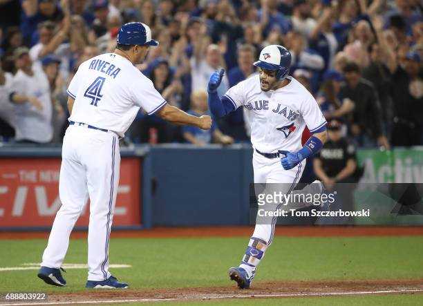 Devon Travis of the Toronto Blue Jays is congratulated by third base coach Luis Rivera after hitting a grand slam home run in the second inning...