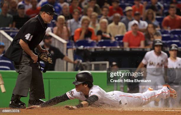 Christian Yelich of the Miami Marlins slides into home to score a run past the tag from Martin Maldonado of the Los Angeles Angels in the first...