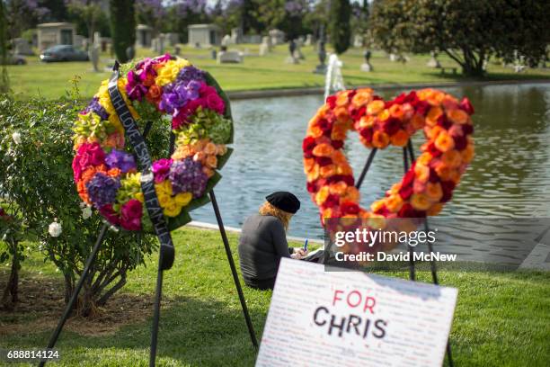 Woman writes near graveside memorial flowers for Chris Cornell after funeral services for Soundgarden frontmanÊChris Cornell were held at Hollywood...