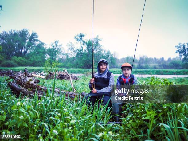 brothers resting on a log while fly-fishing on a trout stream - waders imagens e fotografias de stock