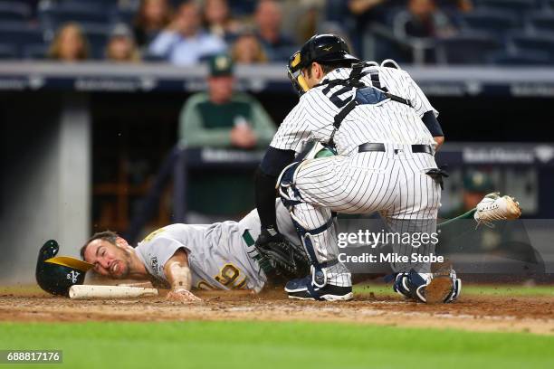 Adam Rosales of the Oakland Athletics is tagged out at home plate by Austin Romine of the New York Yankees in the eighth inning at Yankee Stadium on...