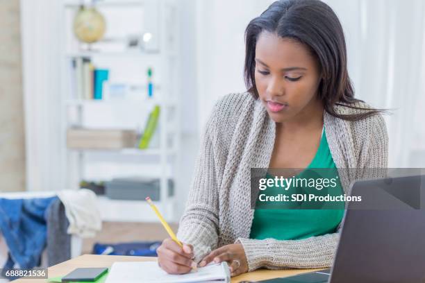 african american teenager concentrates while working on homework assignment - cute college girl stock pictures, royalty-free photos & images
