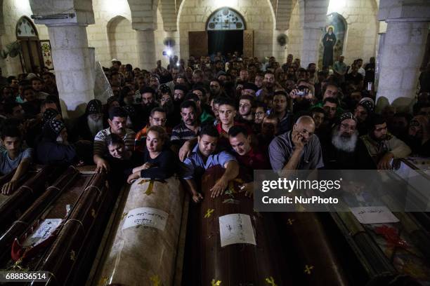 Relatives of Coptic Christians who were killed during a bus attack, surround their coffins, during their funeral service, at Ava Samuel desert...