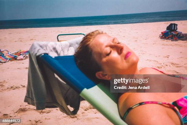 family photo of vintage 90s woman sunbathing on beach - fotostreifen stock-fotos und bilder