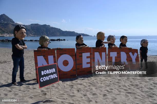 Oxfam activists wearing masks of the leaders of the G7 summit Canadian Prime Minister Justin Trudeau, German Chancellor Angela Merkel, Japanese Prime...