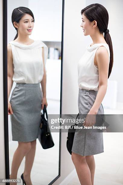 young woman examining herself in front of mirror - sleeveless ストックフォトと画像