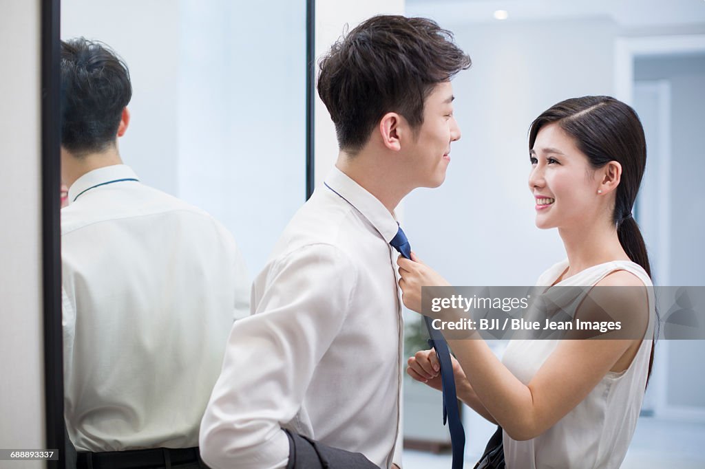 Young woman adjusting husbands tie