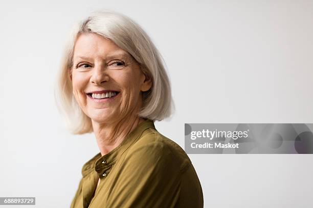 thoughtful senior woman smiling while looking away against white background - old woman side view foto e immagini stock