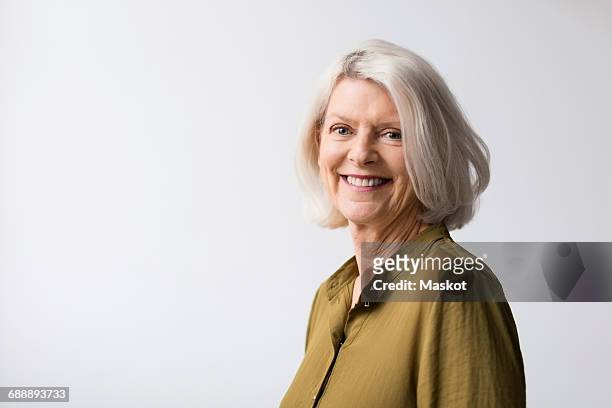 portrait of confident senior woman against white background - short stockfoto's en -beelden