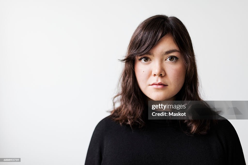Portrait of serious young woman against white background