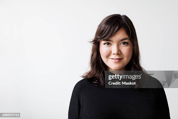 portrait of confident young woman smiling against white background - casual young woman on white background stockfoto's en -beelden