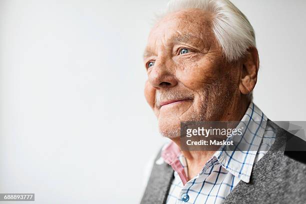 thoughtful senior man smiling while looking away against white background - senior adult white background stock pictures, royalty-free photos & images