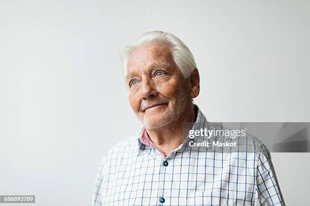 thoughtful senior man smiling while looking away against white background - design thinking white background stock pictures, royalty-free photos & images