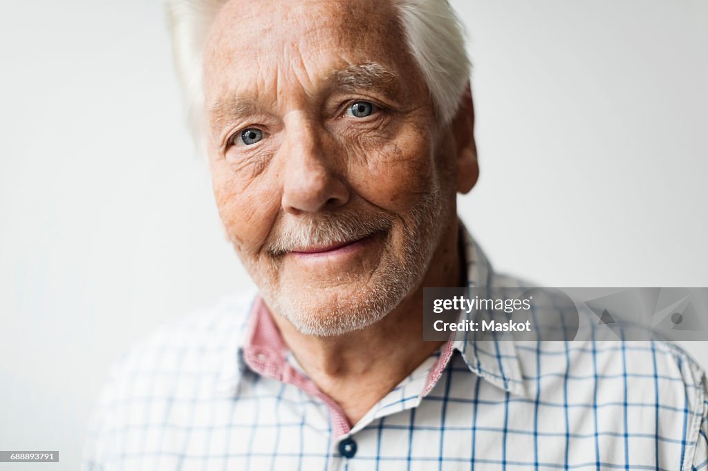 Portrait of smiling senior man against white background