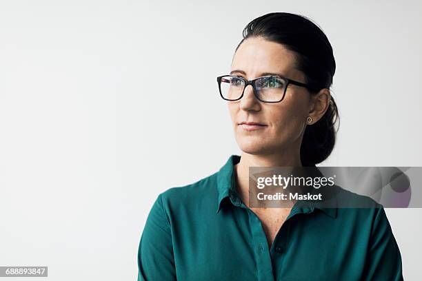 thoughtful mature woman wearing eyeglasses against white background - looking away foto e immagini stock