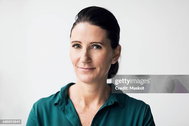 portrait of confident mature woman smiling over white background - green shirt stock pictures, royalty-free photos & images