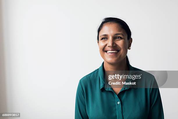 happy mid adult woman looking away while standing against white background - groen shirt stockfoto's en -beelden