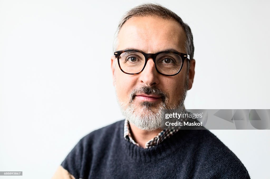 Portrait of confident mature man wearing eyeglasses against white background