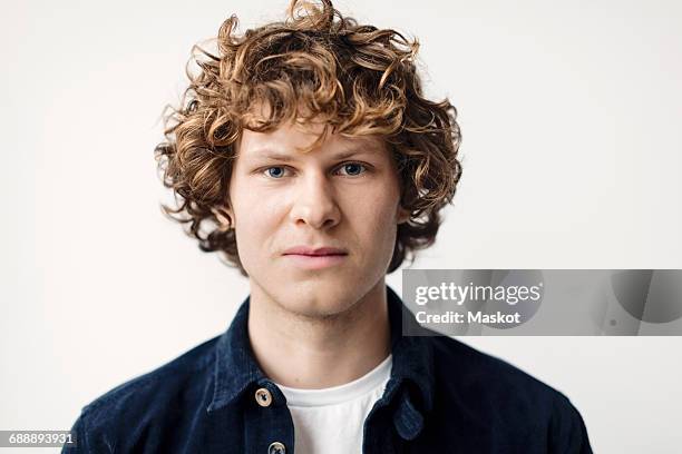 portrait of confident young man against white background - blond undone stock-fotos und bilder