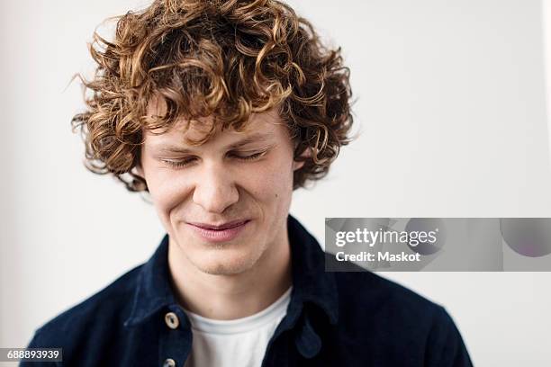 happy young man with eyes closed against white background - blond undone bildbanksfoton och bilder