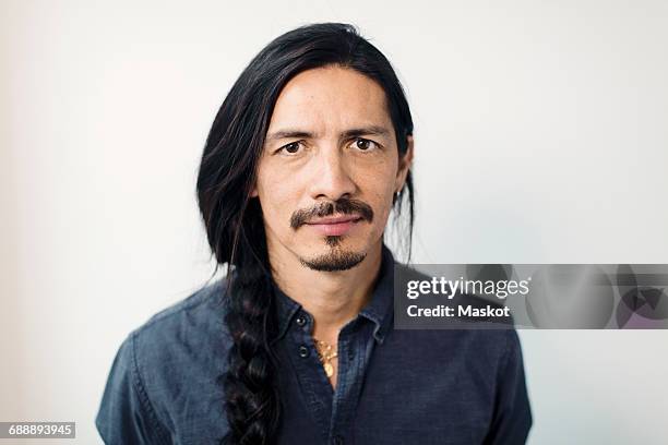 portrait of confident mature man with braided hair against white background - long mustache stock-fotos und bilder