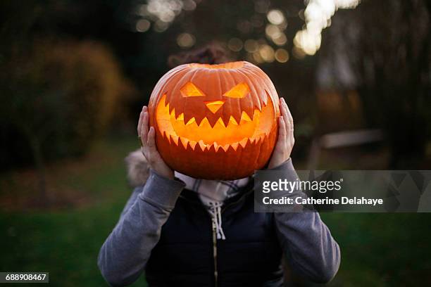 a girl with halloween pumpkin in front of her head - halloween stock pictures, royalty-free photos & images