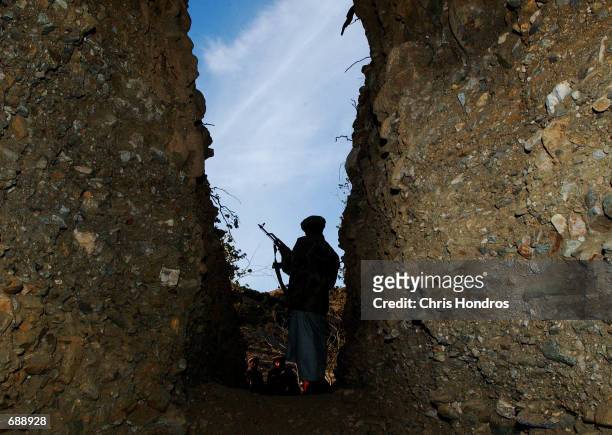 Mujahadeen soldier guards the entrance to a former Al-Qaeda cave December 24, 2001 in Tora Bora, Afghanistan. Al-Qaeda soldiers hid in this and...