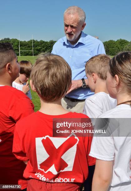 Britain's main opposition Labour party leader Jeremy Corbyn speaks to children during a visit to Hackney Marshes football pitches in London on May 27...