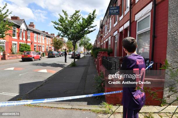 Boy looks on as Police attend the scene of a raid in the Moss Side area as part of their ongoing investigation following the terror attack earlier...