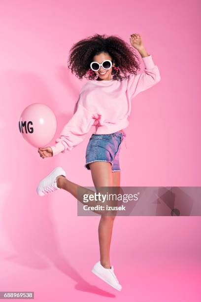 in voller länge portrait von junge afro frau springen - rosa shorts stock-fotos und bilder