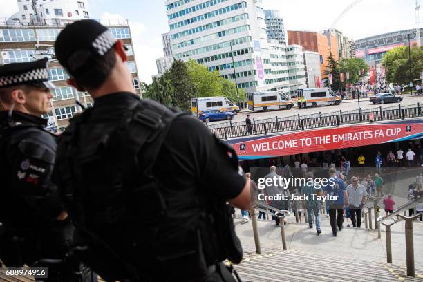 Armed police officers look on as football fans arrive at Wembley Park Tube Station ahead of the FA Cup final on May 27, 2017 in London, England....